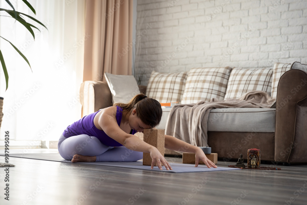 Naklejka premium Young woman practicing yoga at home
