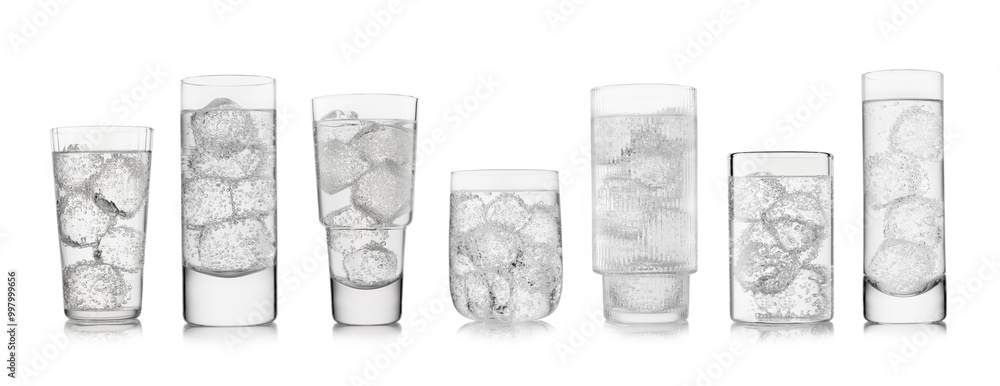 Obraz premium Water sparkling lemonade drink with ice cubes in various shape and size glasses on white background.