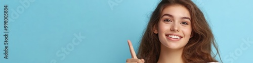 Confident and Poised: A young woman with a bright smile points upward, radiating positivity and enthusiasm against a vibrant blue backdrop. Her gesture suggests a new direction, a brilliant idea.