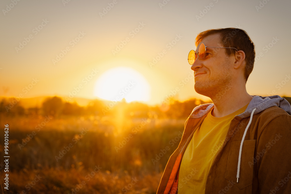 A man enjoys the warm glow of sunset while standing in a serene field during golden hour, reflecting on the day's events A man enjoys the warm glow of sunset while standing in a serene field during golden hour, reflecting on the day's events