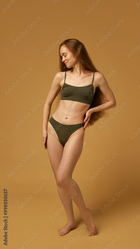Portrait of beautiful young woman with long hair and slim healthy body, posing in underwear against sandy color studio background. Concept of natural female beauty, body and skin care, health Portrait of beautiful young woman with long hair and slim healthy body, posing in underwear against sandy color studio background. Concept of natural female beauty, body and skin care, health