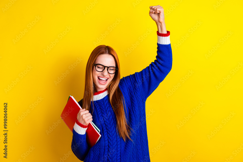 Photo portrait of lovely young lady hold copybooks winning dressed stylish blue knitwear garment isolated on yellow color background Photo portrait of lovely young lady hold copybooks winning dressed stylish blue knitwear garment isolated on yellow color background