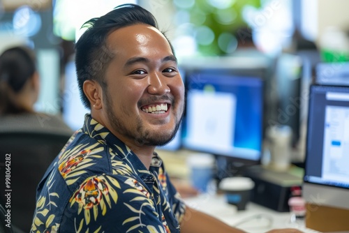 Cheerful Pacific Islander programmer man working with computers in office. , background blur