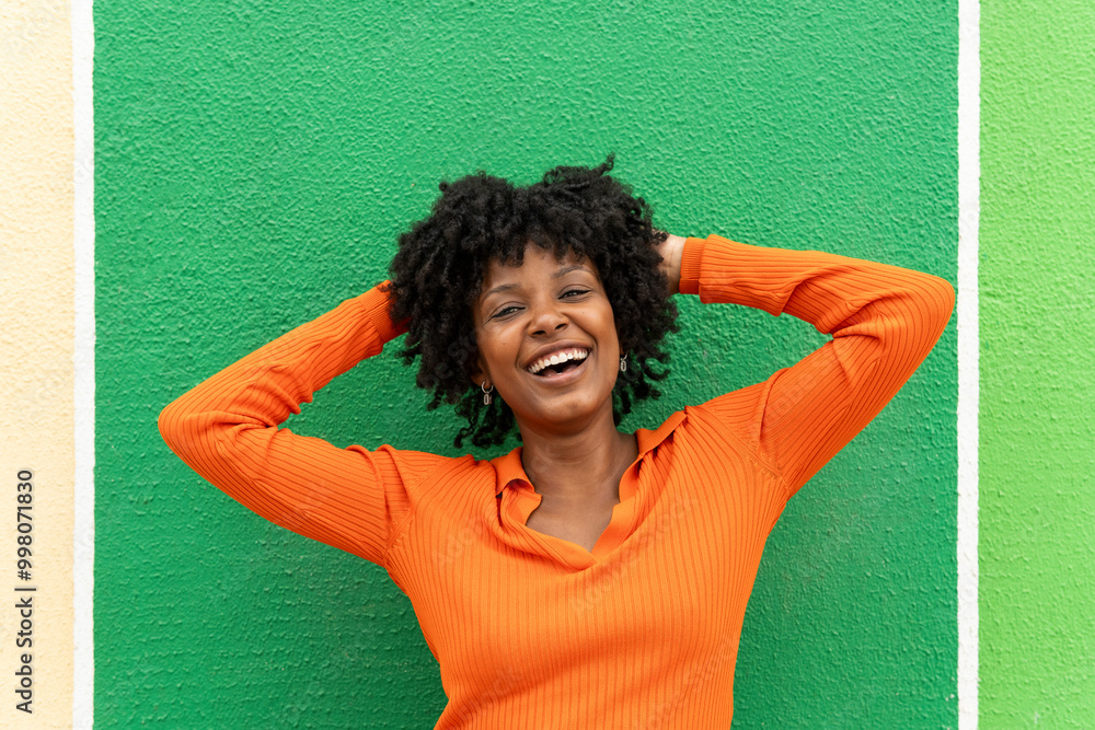 Cheerful woman with hands behind head near green wall Cheerful woman with hands behind head near green wall