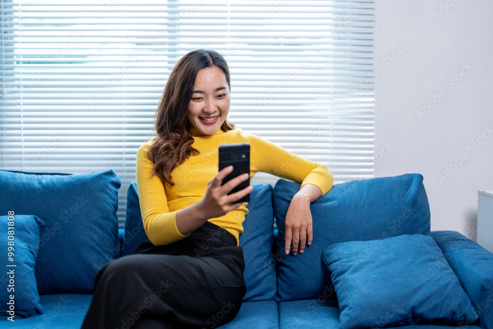 Young asian woman relaxing on sofa using smartphone at home Young asian woman relaxing on sofa using smartphone at home
