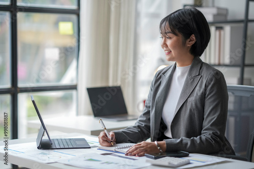 Asian businesswoman working with documents and taking notes in modern office