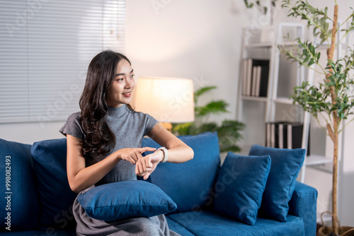 Young woman using smartwatch while relaxing on sofa at home