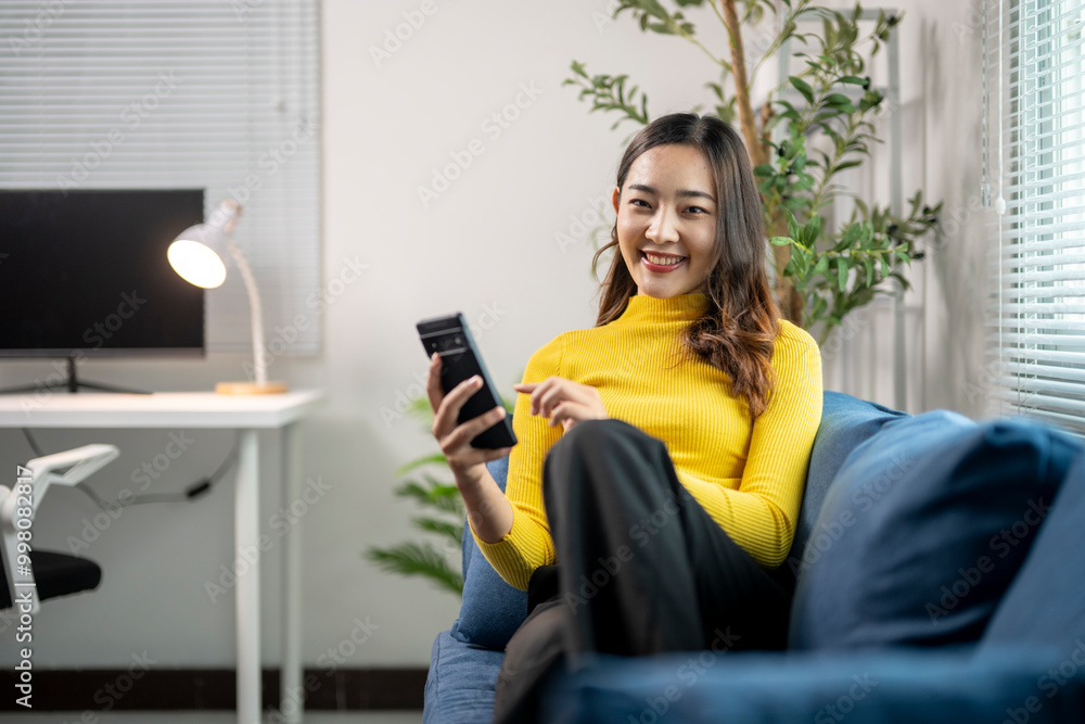 Young asian woman using smartphone while relaxing on sofa at home Young asian woman using smartphone while relaxing on sofa at home