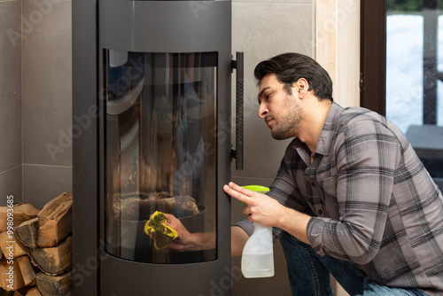 A young man cleans a fireplace to be prepared for the harsh winter during an energy crisis	 photo