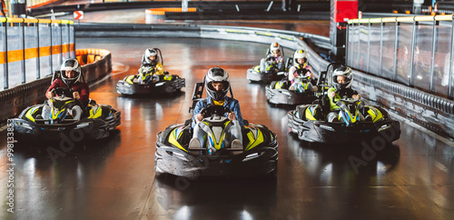 Картината върху платно Young man in a helmet leading a group of racers in a go-kart race on an indoor track
