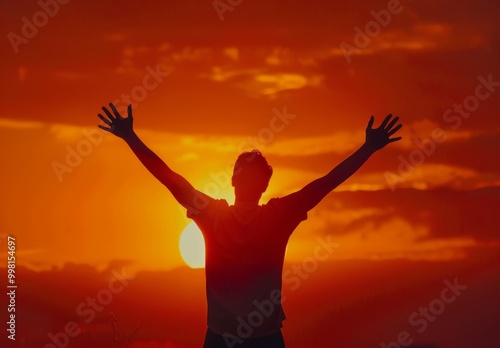 Silhouette of a person celebrating as the sun sets over the horizon during a vibrant orange twilight in a serene outdoor environment