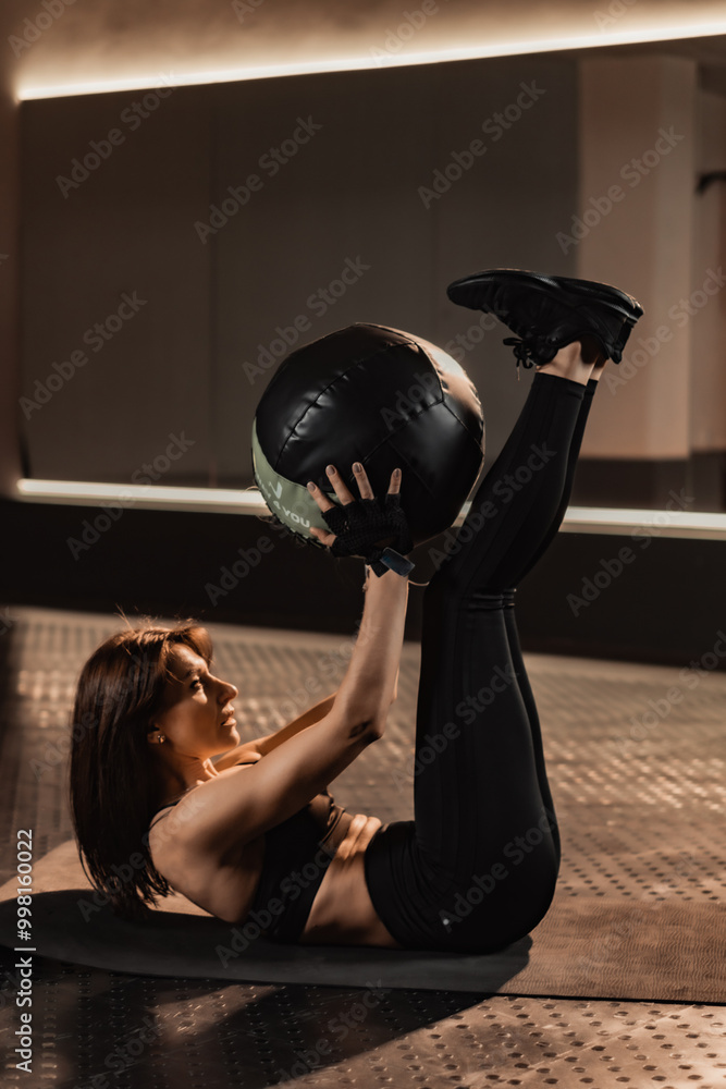 A dedicated woman is expertly executing the medicine ball crunch exercise in a contemporary and wellequipped gym environment, showcasing her commitment to fitness and athletic performance A dedicated woman is expertly executing the medicine ball crunch exercise in a contemporary and wellequipped gym environment, showcasing her commitment to fitness and athletic performance