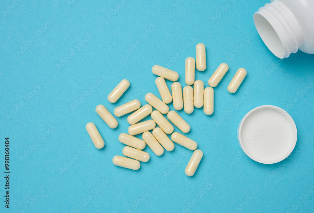 Oval white capsules on a blue background. Medical pills, top view Oval white capsules on a blue background. Medical pills, top view