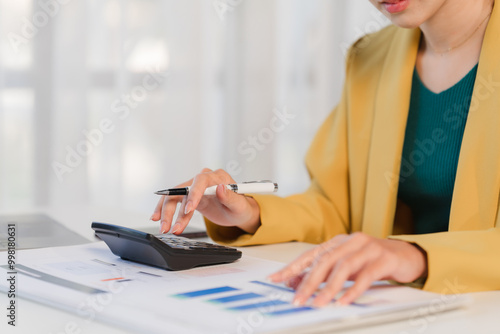 Focused Financial Analysis: A close-up shot of a businesswoman meticulously reviewing financial documents and using a calculator, showcasing dedication and precision.