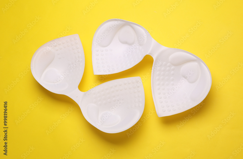 White invisible bras on yellow background. Top view White invisible bras on yellow background. Top view