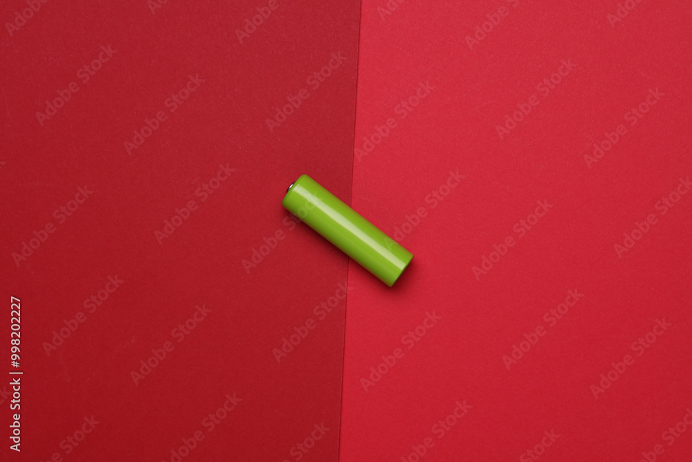 Green AA battery on a red background Green AA battery on a red background