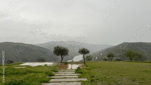 An ethereal scene of the Douro Valley from a high vantage point, showcasing the fog-covered river winding through lush hillsides, with layers of clouds adding depth and mystery to the landscape. photo