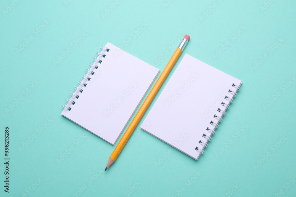 Blank white spiral notebooks with pencil on mint green background Blank white spiral notebooks with pencil on mint green background
