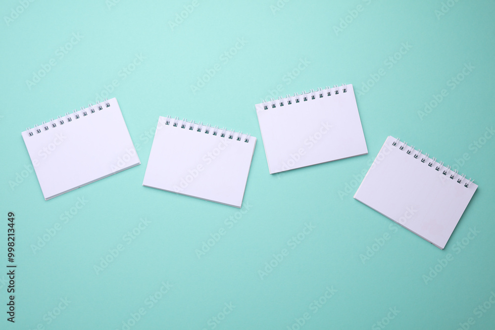 Group of Blank white spiral notebooks on mint green background Group of Blank white spiral notebooks on mint green background