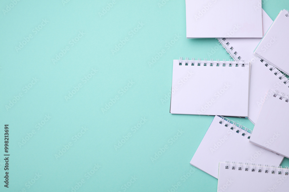 Group of Blank white spiral notebooks on mint green background with copy space Group of Blank white spiral notebooks on mint green background with copy space