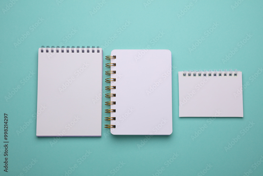 Group of white blank spiral notebooks on mint green background Group of white blank spiral notebooks on mint green background