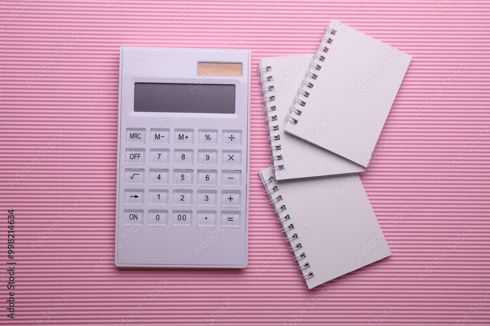 Group of Blank white spiral notebooks with calculator on pink background Group of Blank white spiral notebooks with calculator on pink background