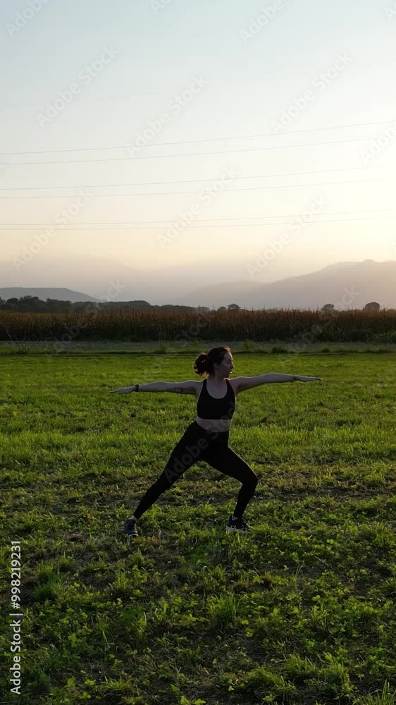 Woman Performing Warrior Yoga Pose, at Sunset in the Countryside, Aerial View Woman Performing Warrior Yoga Pose, at Sunset in the Countryside, Aerial View