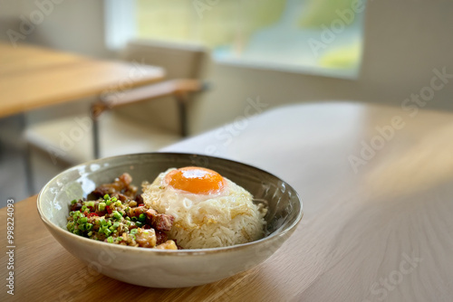 Delicious Bowl of Rice Topped with a Sunny-Side-Up Egg and Stir-Fried Pork, Served in a Minimalist Dining Setting