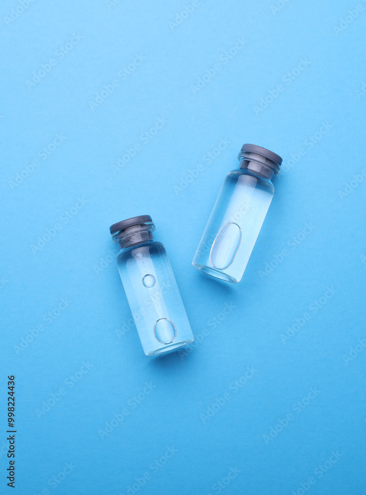 Medical glass vials with liquid on a blue background Medical glass vials with liquid on a blue background