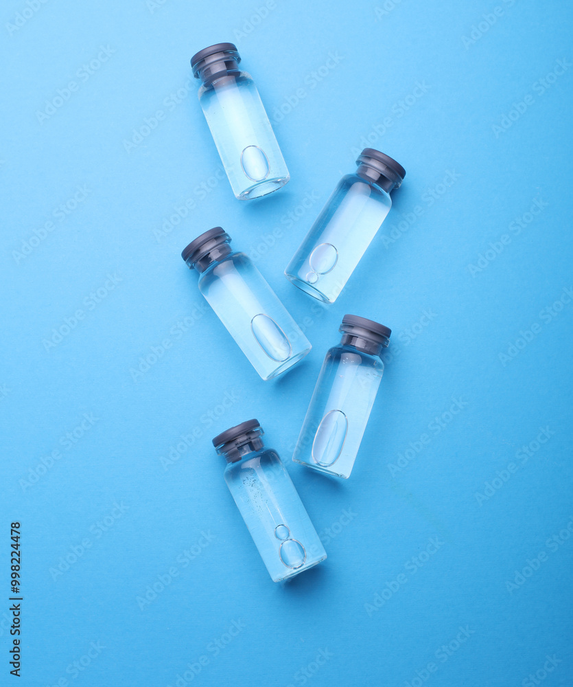 Medical glass vials with liquid on a blue background Medical glass vials with liquid on a blue background