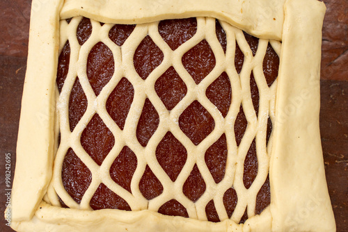 A square of dough with apple jam filling is prepared for the next layer. The process of making a pie, recipe. Bakery, production of flour products photo