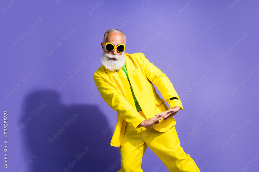 Portrait of funny extravagant aged man clubbing dancing yellow suit isolated on purple color background Portrait of funny extravagant aged man clubbing dancing yellow suit isolated on purple color background