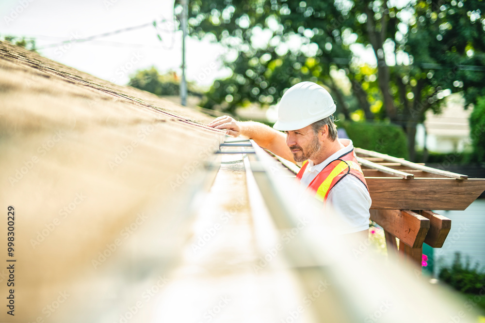 man with hard hat standing on steps inspecting house roof man with hard hat standing on steps inspecting house roof