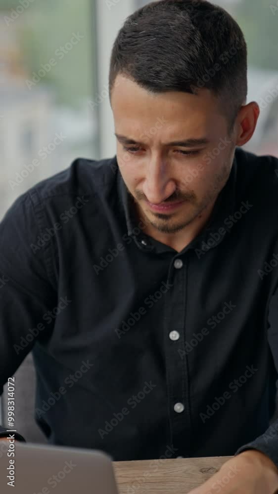 Man with concerned expression on his face looking at laptop. Busy man thinking over his problems at work, hard tasks or challenges. Vertical video Man with concerned expression on his face looking at laptop. Busy man thinking over his problems at work, hard tasks or challenges. Vertical video