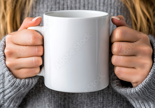  High-resolution mockup of a white coffee mug being held by two hands. The background features a woman wearing a grey sweater with long hair. Created with Ai