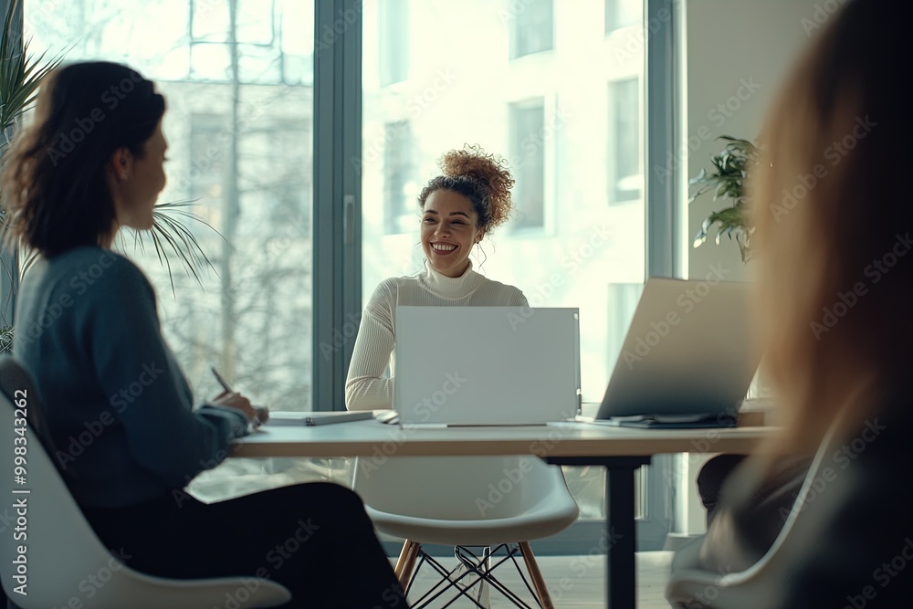 A Business Meeting in a Modern Office With Three Professionals Discussing Ideas Enthusiastically by a Large Window A Business Meeting in a Modern Office With Three Professionals Discussing Ideas Enthusiastically by a Large Window