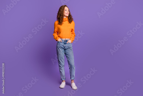 Portrait of pretty young girl look empty space wear orange sweater isolated on purple color background