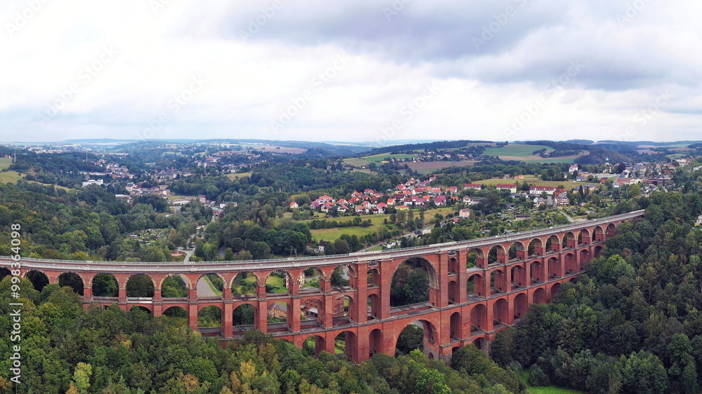 Obraz premium Luftbild der Göltzschtalbrücke, ein beeindruckendes Viadukt aus Ziegelsteinen, das sich majestätisch über das Tal der Göltzsch spannt. 