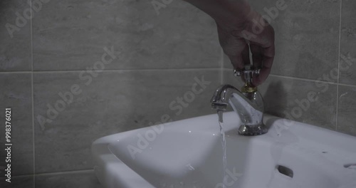 Close up of a man's hand opening the sink faucet.