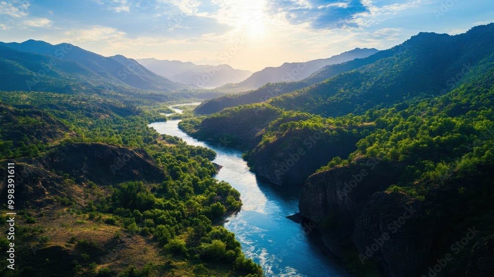 Obraz premium Breathtaking aerial view of a serene river winding through lush green mountains under a vibrant blue sky.