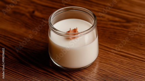 Candle autumn in small amber glass jar with wooden wick on wooden stand on background. Top view