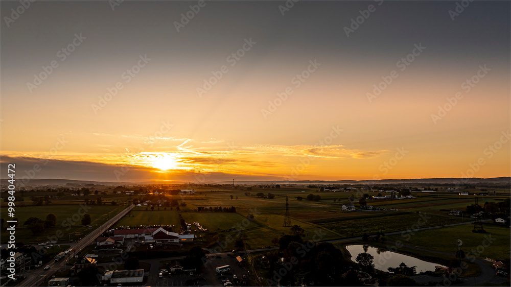 A beautiful sunset paints the sky with warm colors over a serene rural landscape. Fields stretch into the distance, while a calm pond reflects the fading light, creating a peaceful atmosphere. A beautiful sunset paints the sky with warm colors over a serene rural landscape. Fields stretch into the distance, while a calm pond reflects the fading light, creating a peaceful atmosphere.
