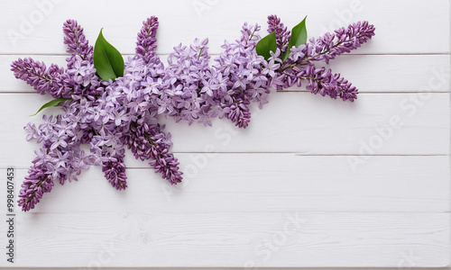 A delicate floral arrangement featuring lilac flowers of various shades—ranging from deep purple to soft lavender and white—artfully placed on a white wooden surface. 