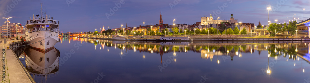 Panoramic view of the Szczecin riverfront along the Oder River in Poland, featuring illuminated historical buildings, docked ships, and the reflection of the skyline in the calm waters Panoramic view of the Szczecin riverfront along the Oder River in Poland, featuring illuminated historical buildings, docked ships, and the reflection of the skyline in the calm waters