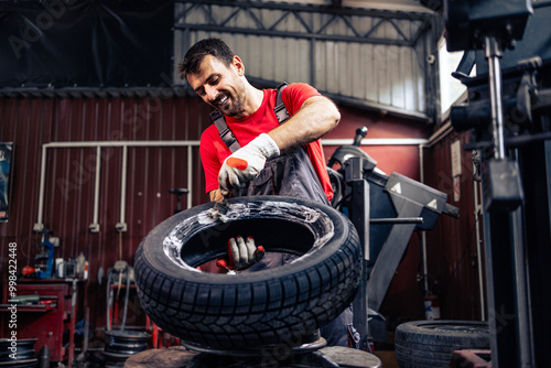 Skilful worker mounting new car tire on the wheel. Changing tires for winter season.