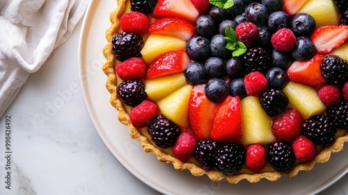 A top view of a fresh fruit tart with vibrant berries and a golden crust, arranged beautifully on a white plate.