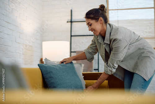 Foto Happy woman  decorating sofa with new pillows.