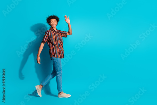 Full size photo of nice young man walk wave hi wear shirt isolated on teal color background photo