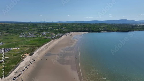 Rossnowlagh Beach, County Donegal, Ireland, June 2023. Drone gradually ascends high above the sandy beach with crystal clear water surrounded by green fields with the Sligo mountains in the distance. photo