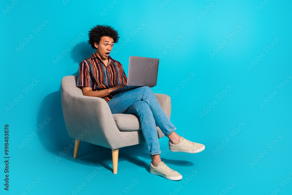 Full body portrait of nice young man sit chair use laptop wear shirt isolated on turquoise color background Full body portrait of nice young man sit chair use laptop wear shirt isolated on turquoise color background